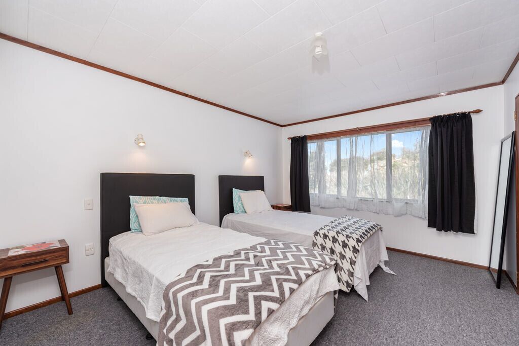 Een hotelkamer met twee bedden, een bureau en een raam met gordijnen.