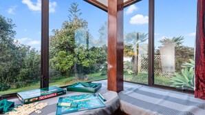 Une pièce dotée d’une grande fenêtre donnant sur un jardin, d’un jeu de Scrabble, de tuiles et d’une boîte de lettres de Scrabble.