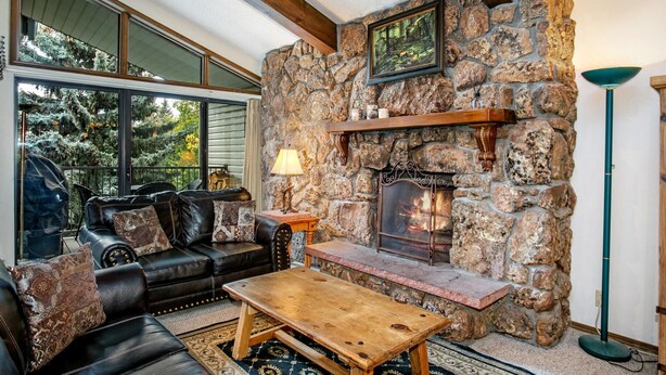 A cozy living room with a stone fireplace, leather furniture, and large windows. - Beaver Creek West 4bd/4ba free Ski shuttle The Perfect Mountain Nest (Avon)