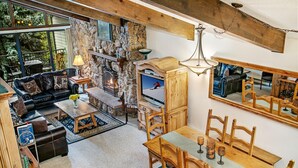 A cozy living area with a stone fireplace, leather sofa, wooden dining table, and a large mirror. - Beaver Creek West 4bd/4ba free Ski shuttle The Perfect Mountain Nest (Avon)