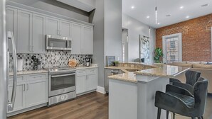 A modern kitchen with grey cabinets, stainless steel appliances, and a central island with bar stools.
