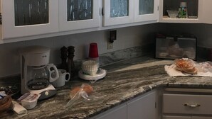 Una cucina con mobili bianchi, una macchina da caffè e un sacchetto di pane sul ripiano.