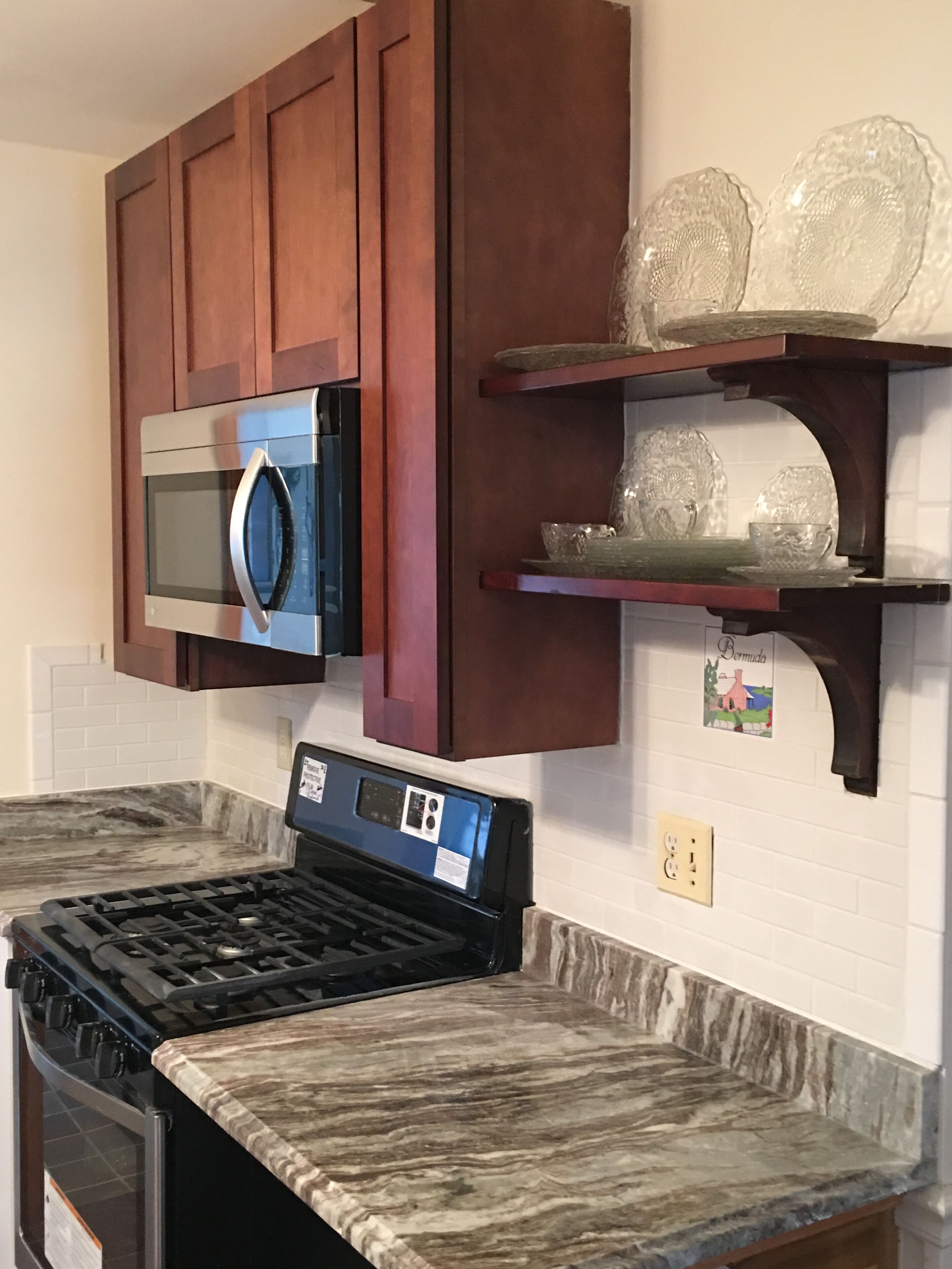 A kitchen with a gas stove, a microwave, and wooden cabinets.