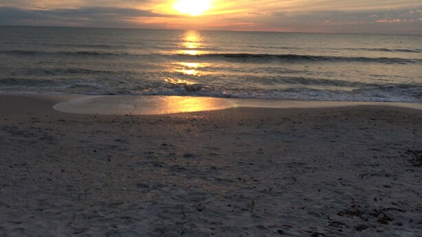 Una spiaggia con un tramonto sull'oceano.