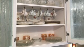 Una cucina con mobili bianchi, bicchieri trasparenti e una macchina da caffè.
