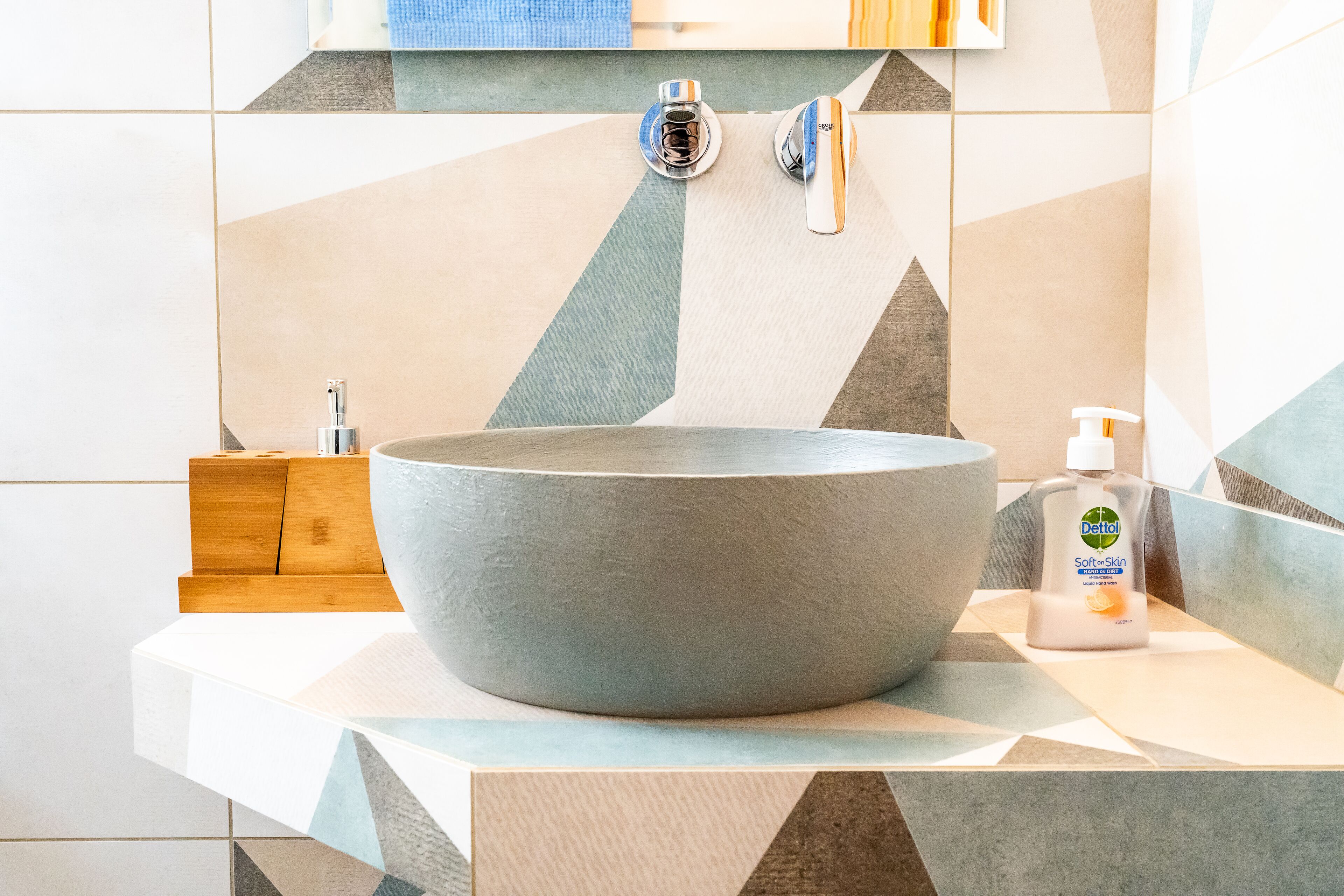 A bathroom with a large, round sink, a soap dispenser, and a towel rack.