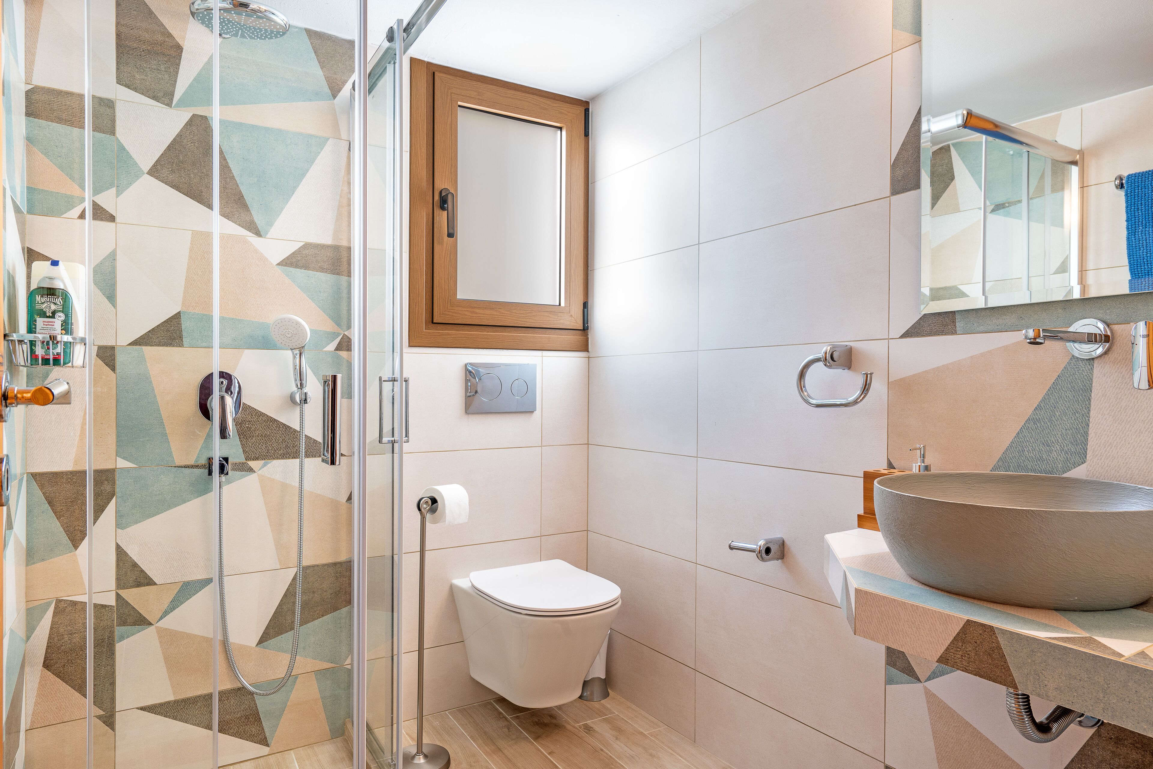 A modern bathroom with a glass shower enclosure, a white toilet, and a large vessel sink.