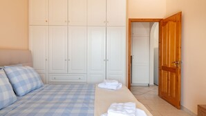 Ein Schlafzimmer mit einem Bett, karierten Bettwäsche, einem Kleiderschrank und einer Holztür.