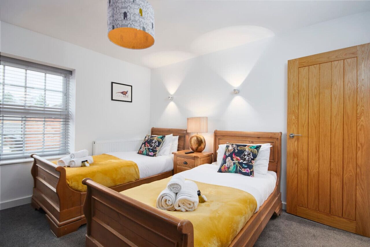 Quarto de hotel com duas camas de madeira, um guarda-roupa espaçoso e uma janela com persianas.