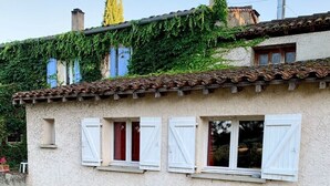 Un bâtiment de style rustique, doté d’une façade blanche, de nombreuses fenêtres avec volets et d’un toit recouvert de tuiles.