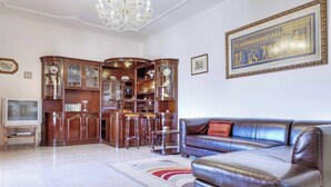 A living room with a leather sofa, wooden cabinets, a television, and a chandelier.