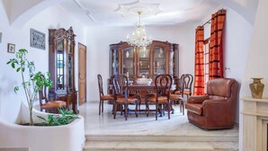 A dining room with a wooden dining table, six chairs, a chandelier, and a large mirror.