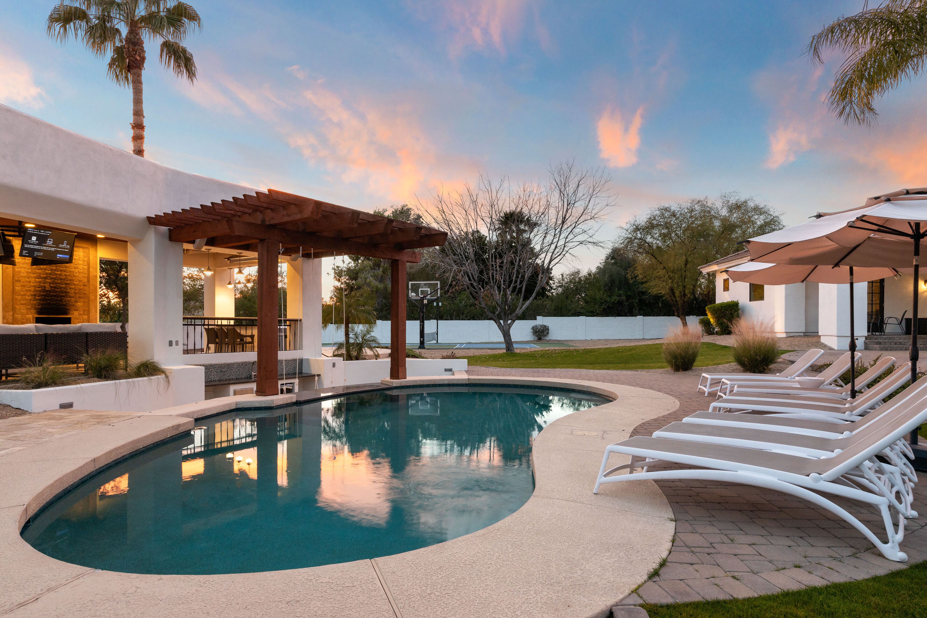 A swimming pool with lounge chairs, a pergola, and a view of a body of water.