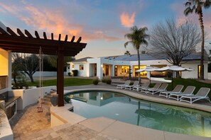 Une maison moderne dotée d’une piscine, d’un espace salon extérieur et d’une pergola.