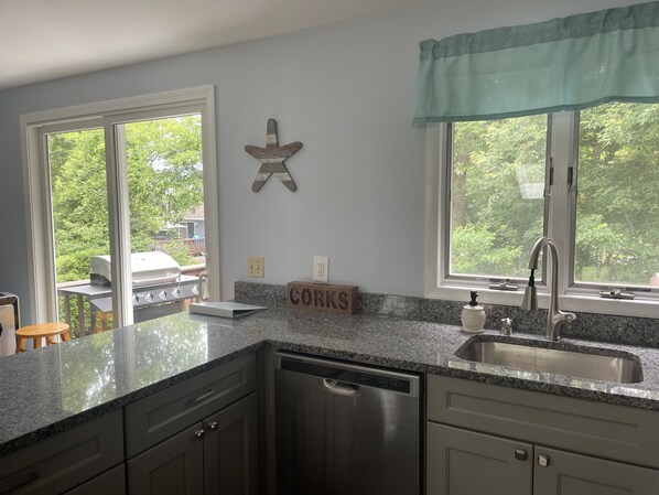 A kitchen with granite countertops, stainless steel appliances, and a view of the outdoors.