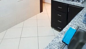 Una cocina con encimera de granito, estufa y armarios de madera oscura.