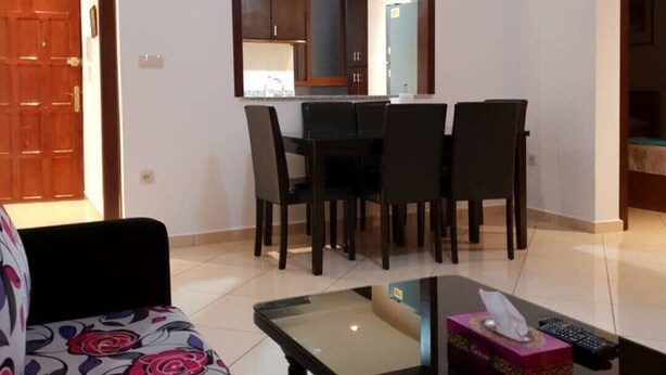 Una sala de estar con sofá, una mesa de centro de vidrio y un comedor con mesa y sillas.
