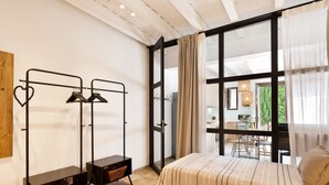 A room with two beds, a wardrobe with hanging space, a small table with a basket, and a large window with curtains. - Sant Mori- La Escala Boutique apartment (Sant Mori)