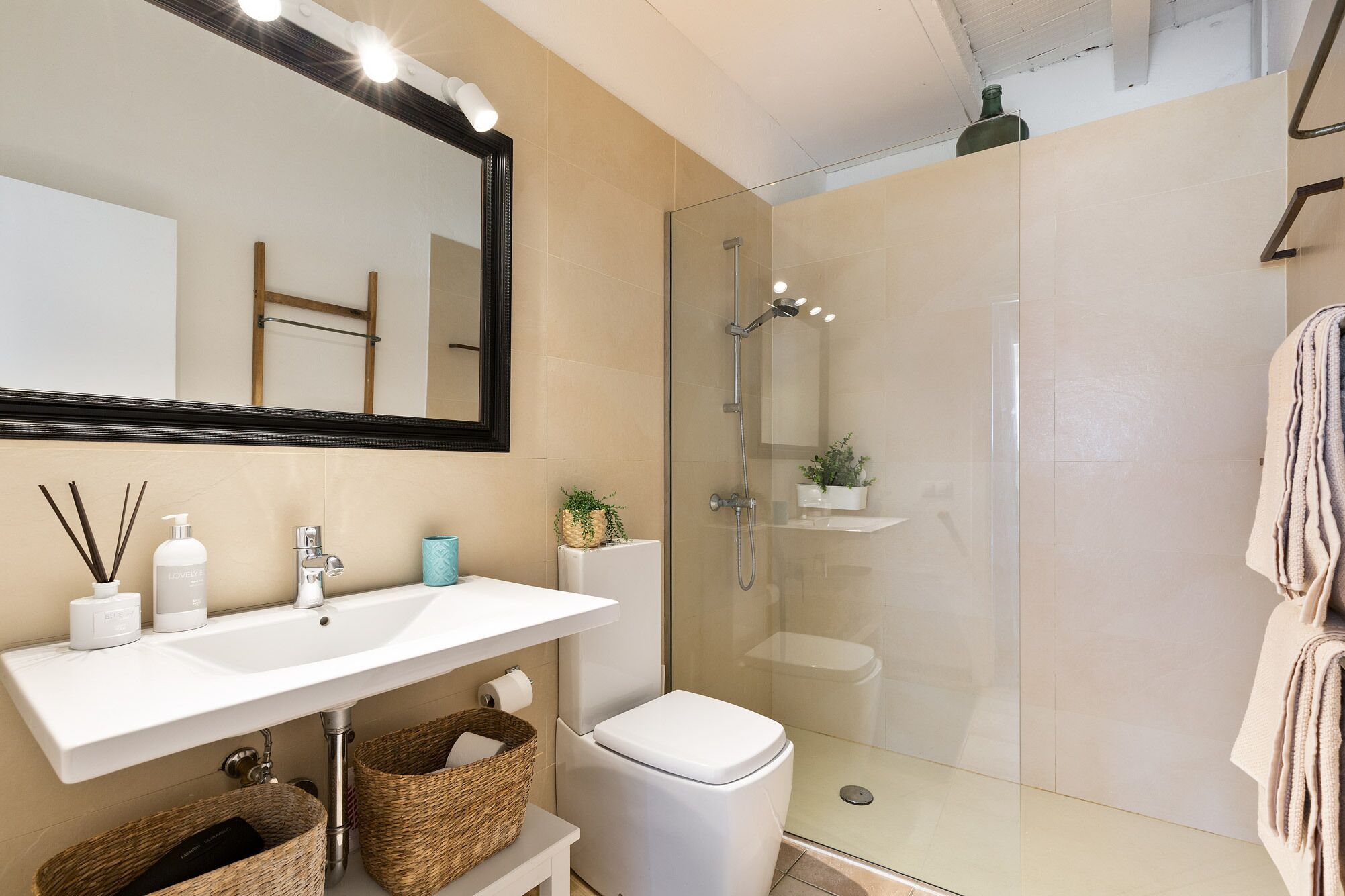 A modern bathroom with a glass shower enclosure, a white sink, and a toilet.