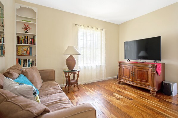 A living room with a sofa, a TV, a bookshelf, and a lamp.