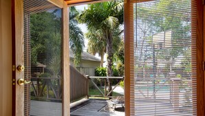 Una puerta de madera con un panel de vidrio y una reja metálica que da a un patio con una parrilla y un piso de madera.