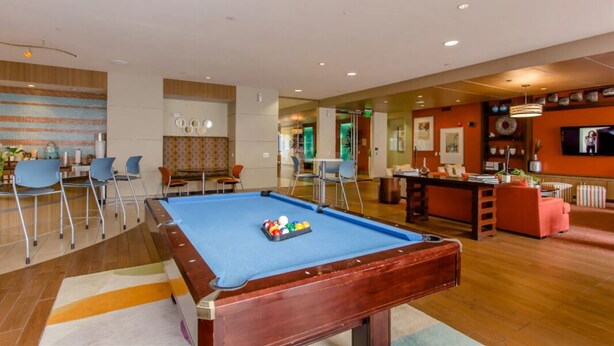 A pool table in a hotel lobby with a bar area and seating. - Houston Modern Apt Pool View NRG DISCOUNTED (Houston)