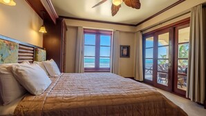 A bedroom with a large bed, a view of the ocean through a sliding door, and a ceiling fan. - 606 - 3rd Floor Ocean View Suite (san pedro)