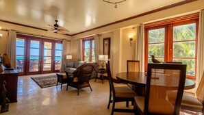 A spacious living room with a large window, a ceiling fan, and a dining area with a table and chairs. - 606 - 3rd Floor Ocean View Suite (san pedro)