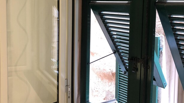 Ein Zimmer mit einem großen Fenster, das eine Glastür und einen Rollladen hat.