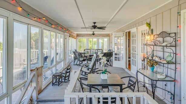 A covered patio with a dining area, large windows, and a ceiling fan. - Luxury Oceanfront Home – Spacious Family Retreat Steps from the Beach (Tybee Island)