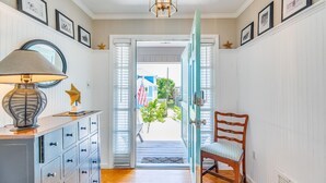 A hallway with a wooden floor, a blue door, a wooden chair, and a lamp on a cabinet. - Luxury Oceanfront Home – Spacious Family Retreat Steps from the Beach (Tybee Island)