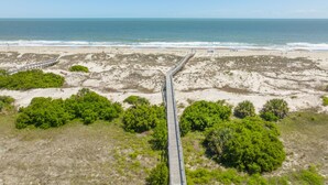 A beach with a wooden boardwalk leading to the shore. - Luxury Oceanfront Home – Spacious Family Retreat Steps from the Beach (Tybee Island)