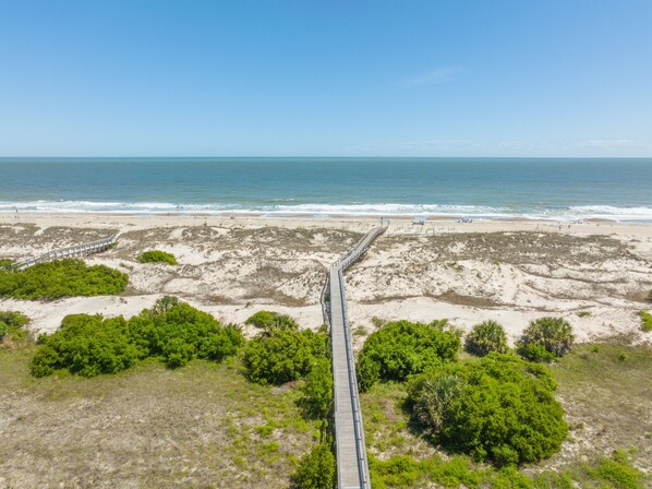 Una playa con un paseo marítimo de madera que conduce a la orilla.