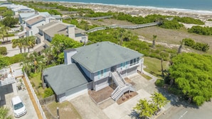 A coastal residential area with a house featuring a large balcony and a staircase leading to the entrance. - Luxury Oceanfront Home – Spacious Family Retreat Steps from the Beach (Tybee Island)