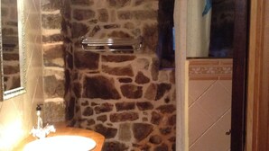 A bathroom with a stone wall, a wooden sink, and a shower area. - TREASURE HOUSE IN RESERVE OF THE BIOSPHERE PICOS DE EUROPA (Cangas de Onís)