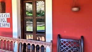A red wall with a window, a sign reading "CASA DEL ESORO", and a metal hanging object. - TREASURE HOUSE IN RESERVE OF THE BIOSPHERE PICOS DE EUROPA (Cangas de Onís)