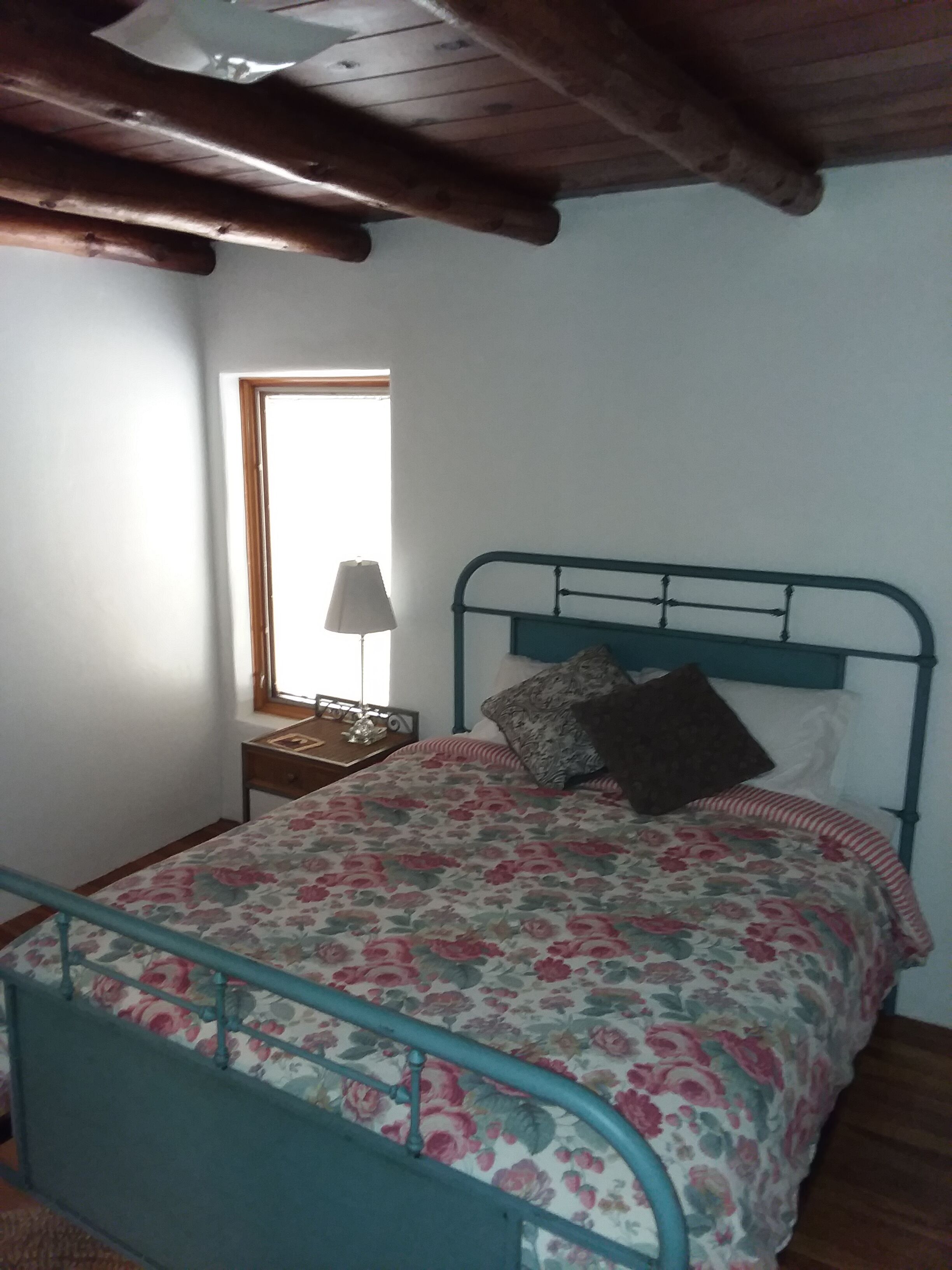 A bedroom with a bed, a window, and a lamp.