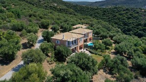 A two-story house with a tiled roof, surrounded by dense greenery and hills in the background. - Lovely house with private pool (Unknown)