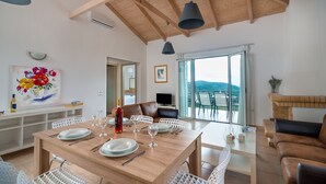 A dining area with a wooden table set for four, a sofa, and a TV in a corner. - Lovely house with private pool (Unknown)