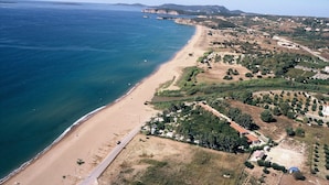 An aerial view of a coastal area with a sandy beach, a road running parallel to the shore, and scattered buildings. - Lovely house with private pool (Unknown)