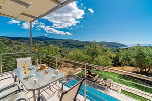 A balcony with a table set for two, overlooking a pool and a scenic landscape. - Lovely house with private pool (Unknown)