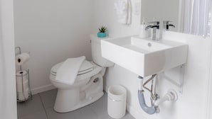 Um banheiro moderno com pia, vaso sanitário e espelho brancos.