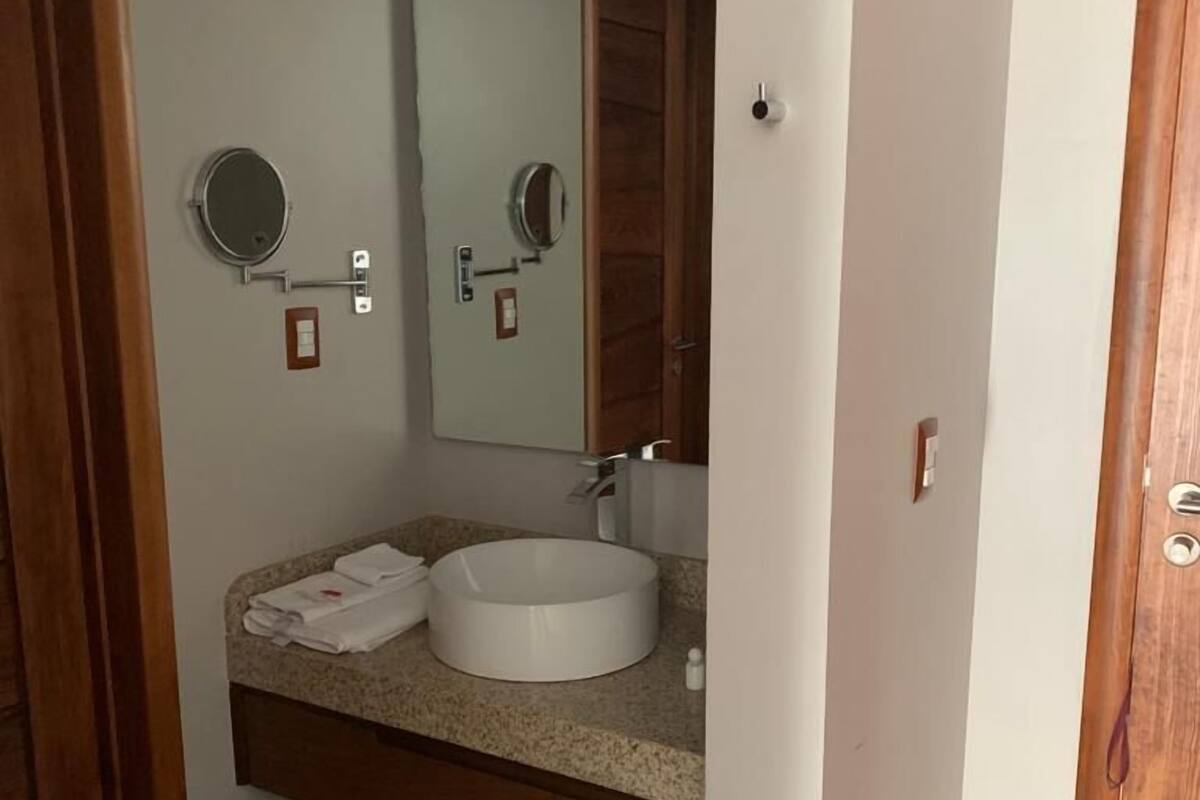 Ein Badezimmer mit einem runden Waschbecken, einem Spiegel und einem Handtuchhalter.