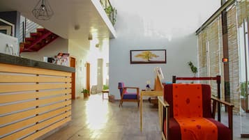 Amplia sala de estar con un mostrador de recepción de madera, un sillón rojo y un cuadro en la pared.