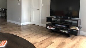 A living room with a flat-screen TV on a black stand, wooden flooring, and a white door. - New Luxury Condo in Downtown Salida #0677 (Salida)