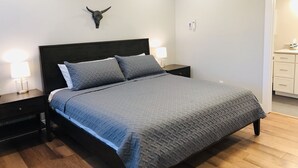 A bedroom with a bed, two bedside tables, a wall-mounted air conditioner, and a door leading to a bathroom. - New Luxury Condo in Downtown Salida #0677 (Salida)