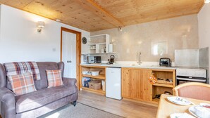Un espacio habitable compacto con kitchenette, un sofá y una mesa de comedor.