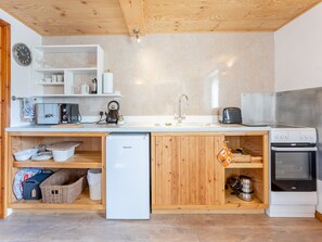Une cuisine compacte équipée d’un réfrigérateur, d’un four à micro-ondes, d’une bouilloire, d’un grille-pain, d’un évier et d’une cuisinière.
