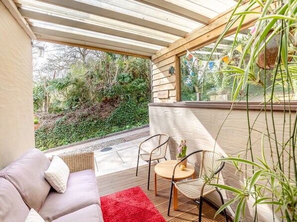 A covered outdoor seating area with a sofa, chairs, and a table.