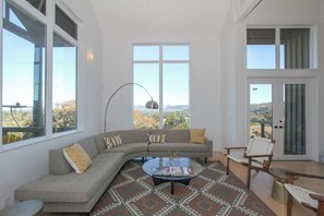 A modern living room with a curved sofa, a coffee table, and a view of the outdoors.